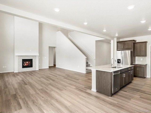 1612 Colorado River Dr, Windsor, CO 80550 - kitchen with appliances with stainless steel finishes, dark brown cabinetry, a center island with sink, light wood finished floors, and recessed lighting