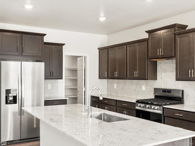 1612 Colorado River Dr, Windsor, CO 80550 - kitchen with stainless steel appliances, dark brown cabinetry, decorative backsplash, an island with sink, and recessed lighting