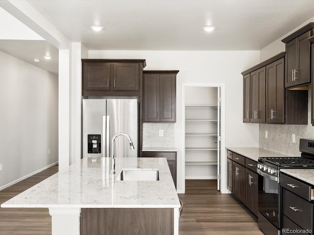 1612 Colorado River Dr, Windsor, CO 80550 - kitchen featuring appliances with stainless steel finishes, an island with sink, dark brown cabinets, light stone countertops, and recessed lighting