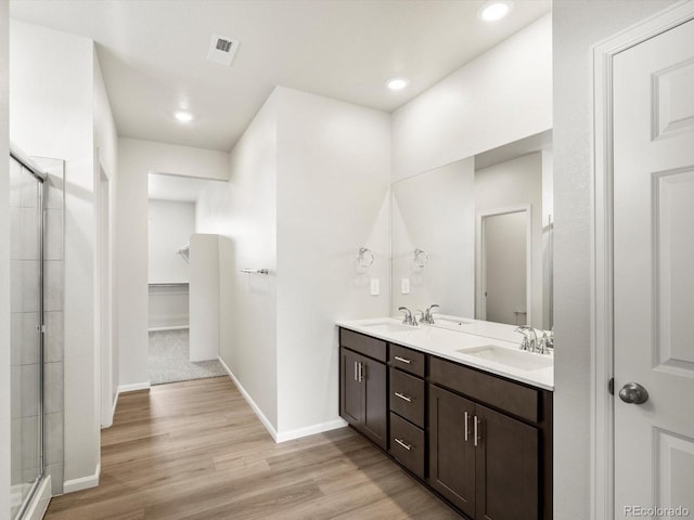 1612 Colorado River Dr, Windsor, CO 80550 - full bathroom with double vanity, a stall shower, wood finished floors, recessed lighting, and a spacious closet