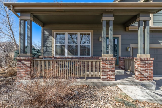 property entrance with a garage, brick siding, and covered porch