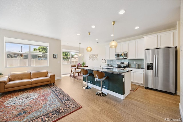4177 E 98th Pl, Thornton, CO 80229 - kitchen with stainless steel appliances, a breakfast bar, light wood finished floors, backsplash, and open floor plan