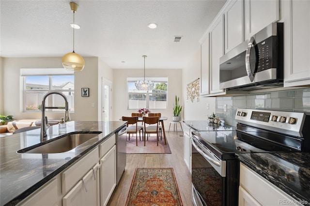 4177 E 98th Pl, Thornton, CO 80229 - kitchen featuring stainless steel appliances, light wood-style floors, hanging light fixtures, dark stone countertops, and recessed lighting