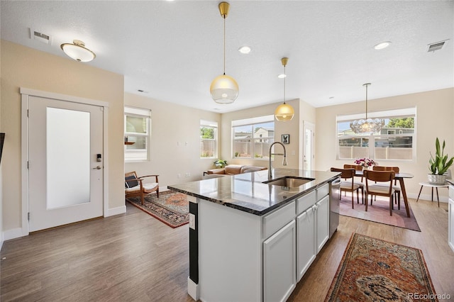4177 E 98th Pl, Thornton, CO 80229 - kitchen with wood finished floors, pendant lighting, an island with sink, recessed lighting, and dark stone countertops