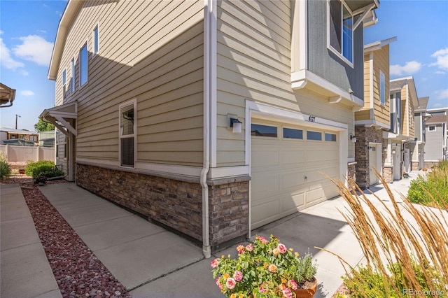 4177 E 98th Pl, Thornton, CO 80229 - view of side of home with stone siding, a garage, and concrete driveway