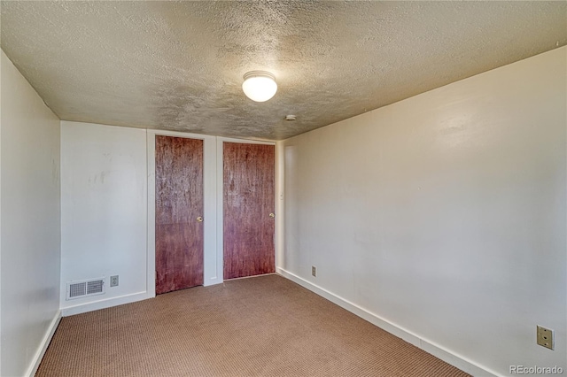 unfurnished bedroom with two closets, a textured ceiling, and carpet flooring