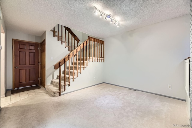 entrance foyer with carpet, stairs, and a textured ceiling