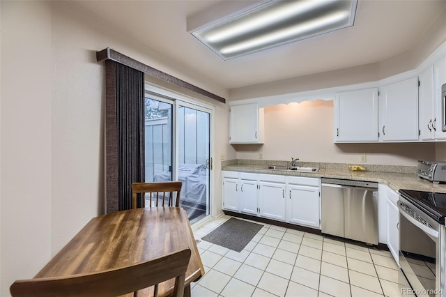 kitchen with appliances with stainless steel finishes, white cabinetry, a sink, and light tile patterned floors