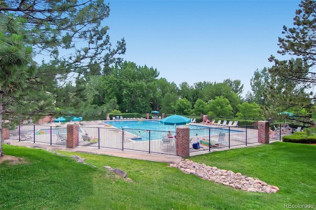 community pool with a yard, a patio area, and fence