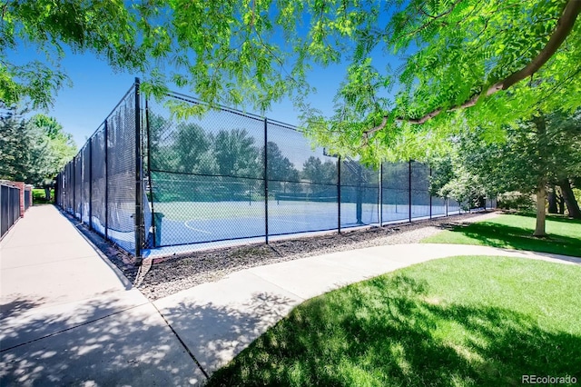 view of tennis court featuring a yard and fence