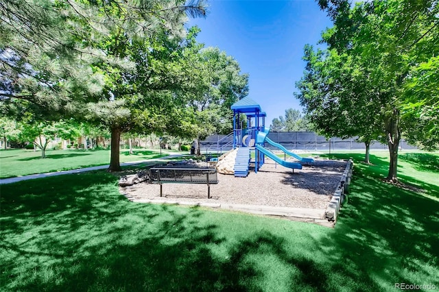 community jungle gym featuring a lawn and fence