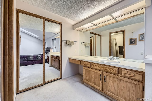 bathroom with vanity, a textured ceiling, and ensuite bathroom