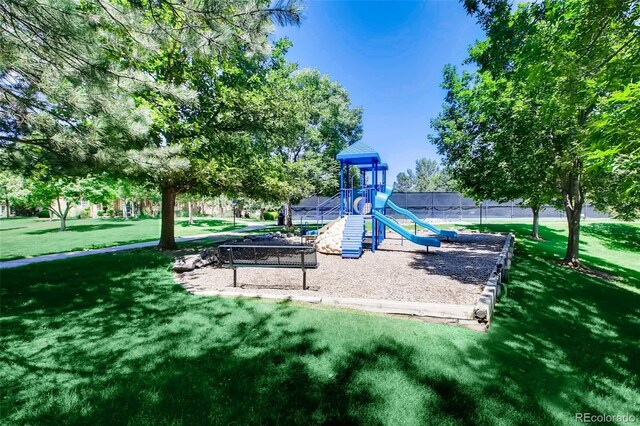 communal playground featuring a lawn and fence