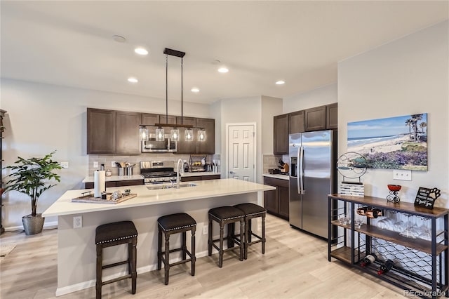 kitchen with decorative light fixtures, decorative backsplash, dark brown cabinetry, and stainless steel appliances