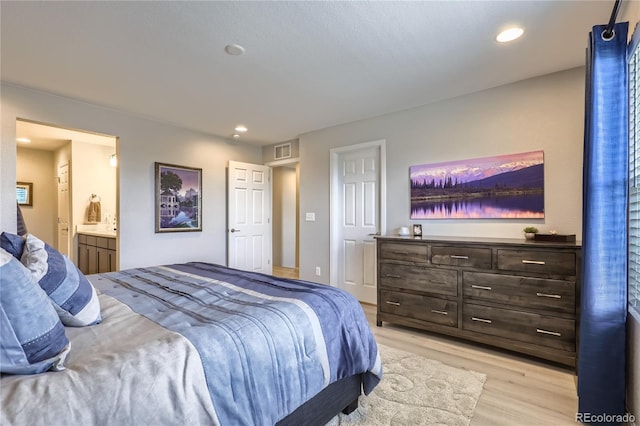 bedroom featuring ensuite bath and light hardwood / wood-style floors