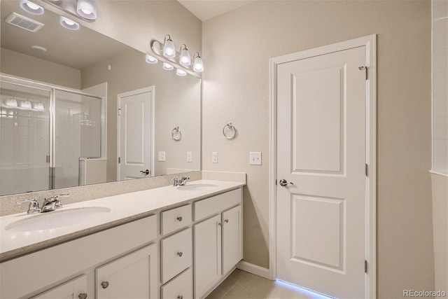 bathroom with tile patterned flooring, a shower with door, and vanity