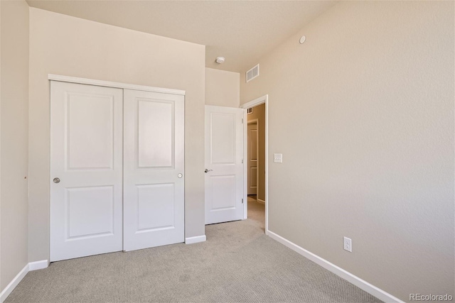 unfurnished bedroom featuring a closet and light carpet