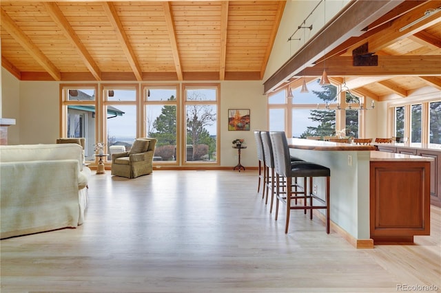 25803 Aspen Way, Golden, CO 80401 - kitchen with wood ceiling with exposed beams, open floor plan, a kitchen breakfast bar, light wood finished floors, and high vaulted ceiling