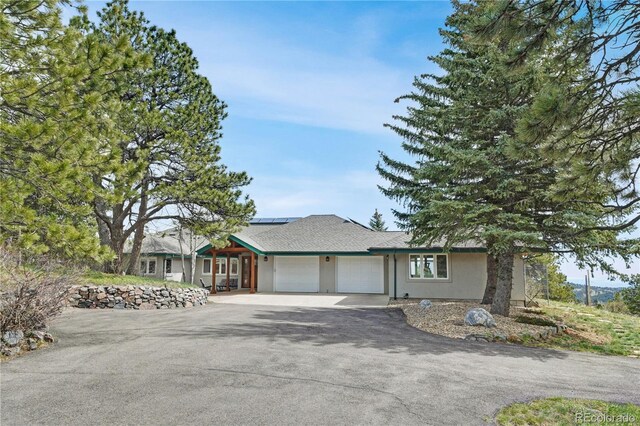 25803 Aspen Way, Golden, CO 80401 - view of front facade with asphalt driveway, a garage, roof mounted solar panels, and stucco siding