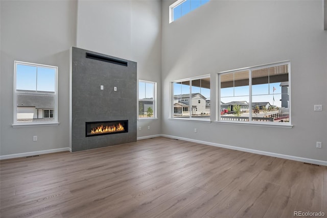 3394 N Grand Baker Ct, Aurora, CO 80019 - unfurnished living room featuring a towering ceiling, wood finished floors, and a tile fireplace