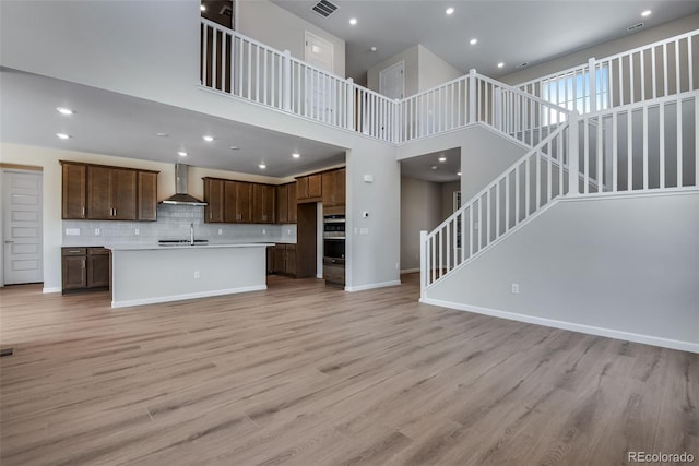 3394 N Grand Baker Ct, Aurora, CO 80019 - unfurnished living room with stairs, light wood finished floors, a high ceiling, and recessed lighting