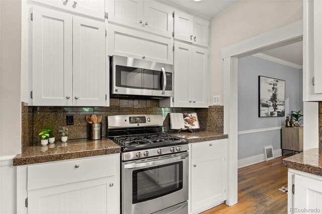 864 Garfield St, Denver, CO 80206 - kitchen with appliances with stainless steel finishes, ornamental molding, white cabinets, tasteful backsplash, and light wood-type flooring
