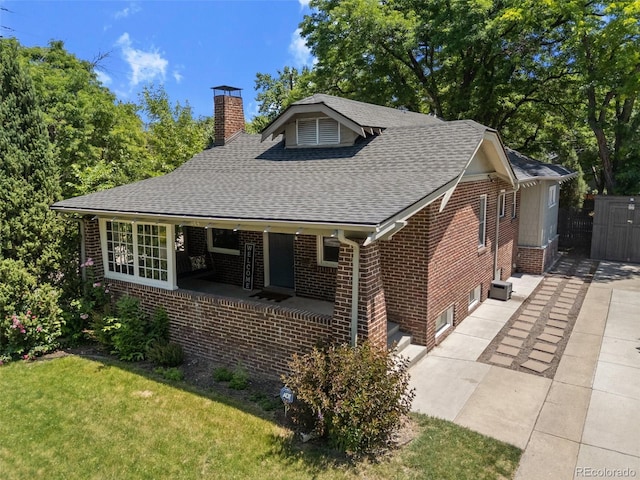 864 Garfield St, Denver, CO 80206 - view of front of house featuring brick siding, a chimney, roof with shingles, a front yard, and covered porch