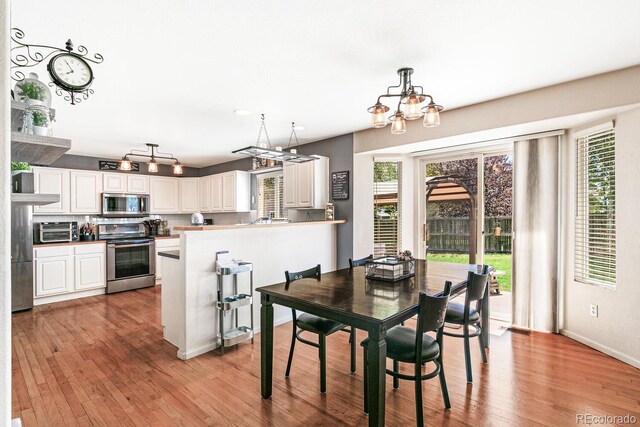 dining area with a notable chandelier, light wood-type flooring, and a wealth of natural light