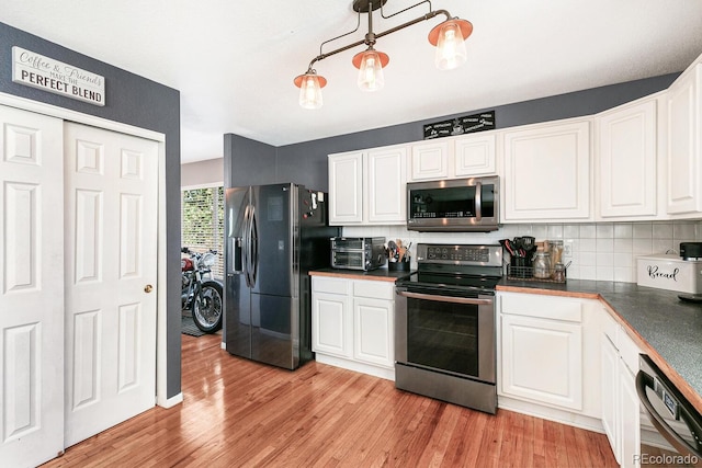 kitchen with pendant lighting, backsplash, white cabinetry, light wood-type flooring, and stainless steel appliances