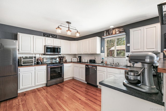 kitchen featuring light hardwood / wood-style flooring, appliances with stainless steel finishes, sink, backsplash, and white cabinetry