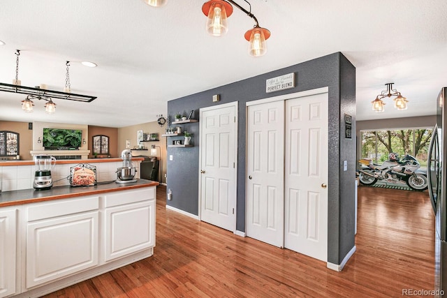 kitchen featuring hardwood / wood-style floors, white cabinets, and pendant lighting