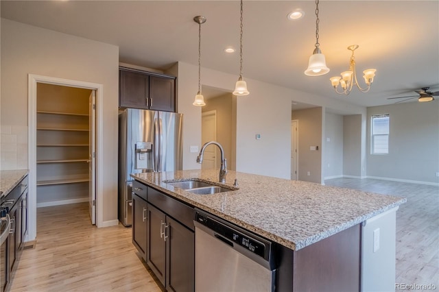 kitchen featuring dark brown cabinets, ceiling fan with notable chandelier, a sink, appliances with stainless steel finishes, and light wood-style floors
