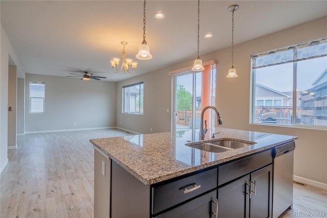 kitchen with stainless steel dishwasher, light wood-style floors, hanging light fixtures, and a sink