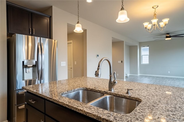 kitchen featuring pendant lighting, ceiling fan with notable chandelier, stainless steel refrigerator with ice dispenser, and a sink
