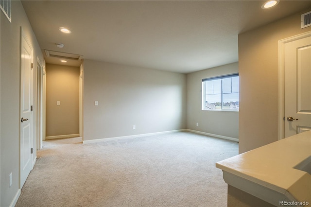 unfurnished living room with light colored carpet, attic access, baseboards, and recessed lighting