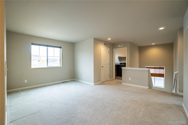 empty room with light colored carpet, visible vents, and a healthy amount of sunlight