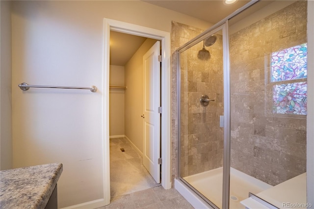 bathroom with a stall shower, baseboards, and tile patterned floors