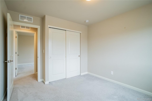 unfurnished bedroom featuring light colored carpet, a closet, baseboards, and visible vents