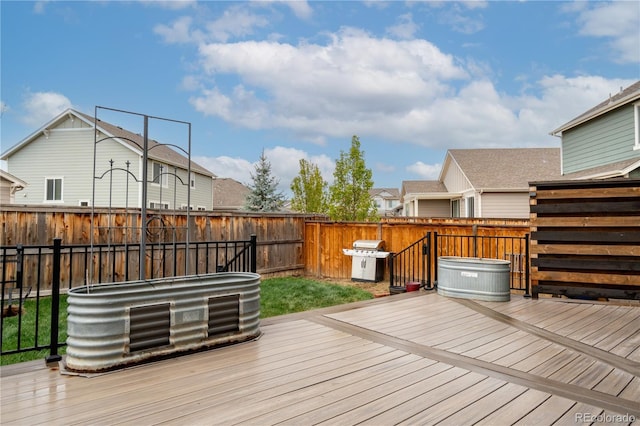 wooden terrace featuring a fenced backyard, grilling area, a hot tub, and a residential view