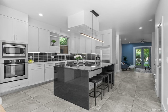 2745 Java Ct, Denver, CO 80211 - kitchen featuring stainless steel appliances, open shelves, tasteful backsplash, white cabinetry, and a kitchen bar