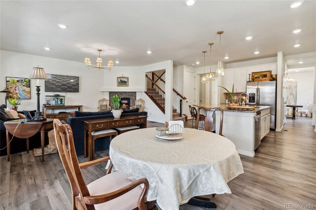 14938 Vienna Cir, Parker, CO 80134 - dining space featuring a chandelier, stairway, a glass covered fireplace, light wood-style flooring, and recessed lighting