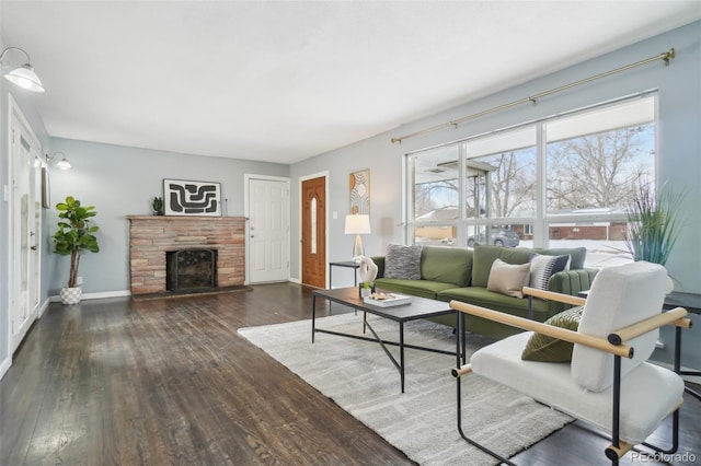 living room featuring dark wood-style floors, a fireplace with raised hearth, and baseboards