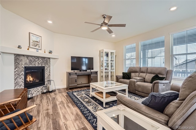 living room featuring a wealth of natural light, a fireplace, a ceiling fan, and wood finished floors