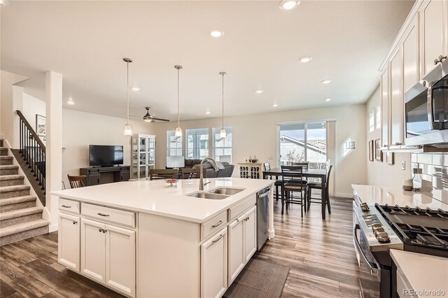 kitchen with wood finished floors, light countertops, a sink, hanging light fixtures, and stainless steel appliances