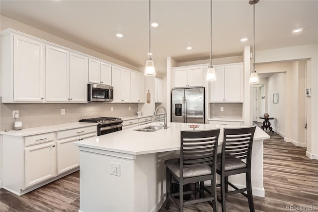 kitchen with a sink, a kitchen island with sink, stainless steel appliances, dark wood-type flooring, and backsplash