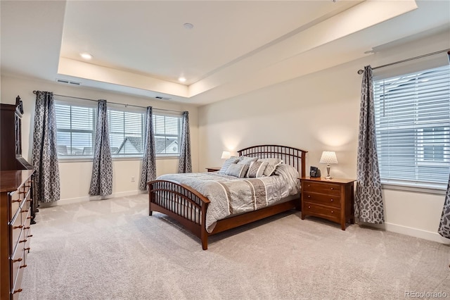 bedroom with light carpet, visible vents, baseboards, and a raised ceiling