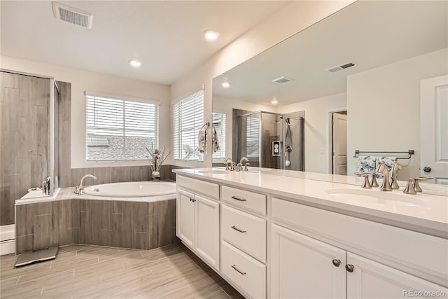 bathroom featuring a stall shower, a garden tub, a sink, and visible vents