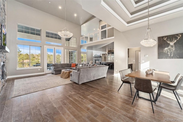 living room featuring a tray ceiling, a stone fireplace, and wood-type flooring