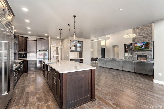 kitchen featuring a center island with sink, sink, pendant lighting, and dark brown cabinetry