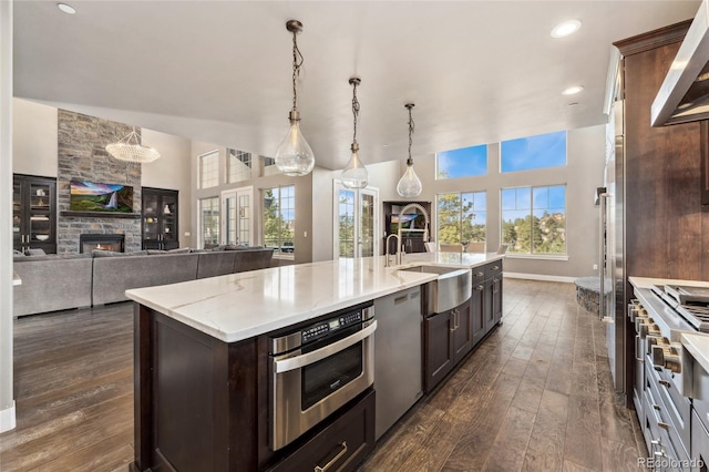 kitchen with pendant lighting, an island with sink, sink, dark brown cabinetry, and stainless steel appliances